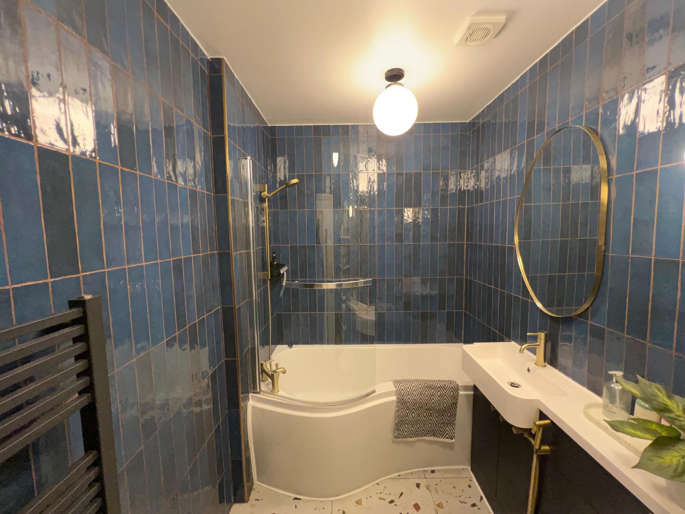 Bathroom with bath, shower screen and blue tiling