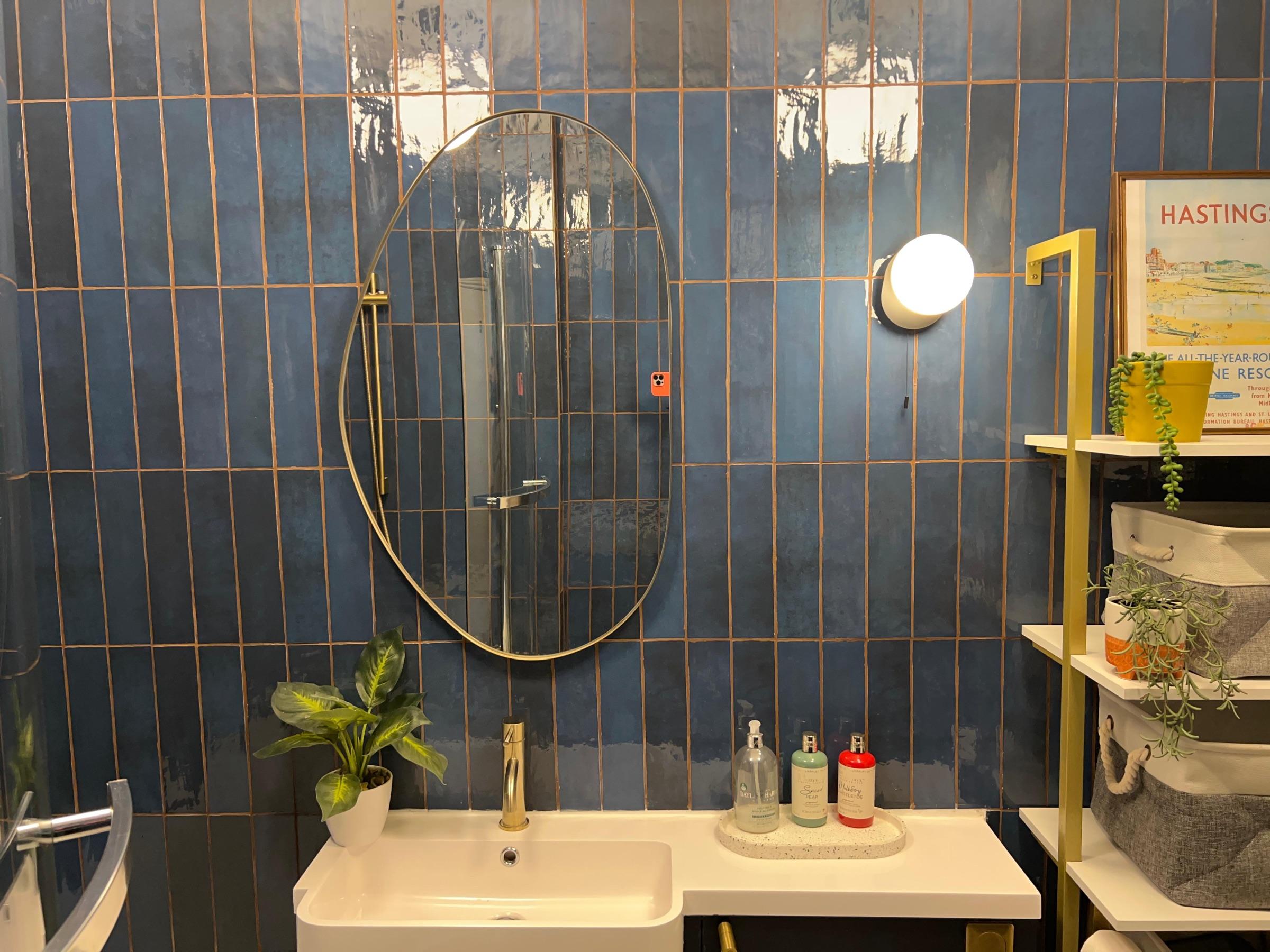 Oval brass mirror on glazed blue tiles