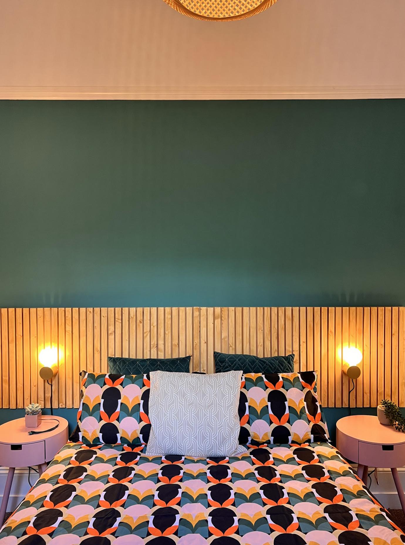 Teal bedroom wall with slatted timber headboard